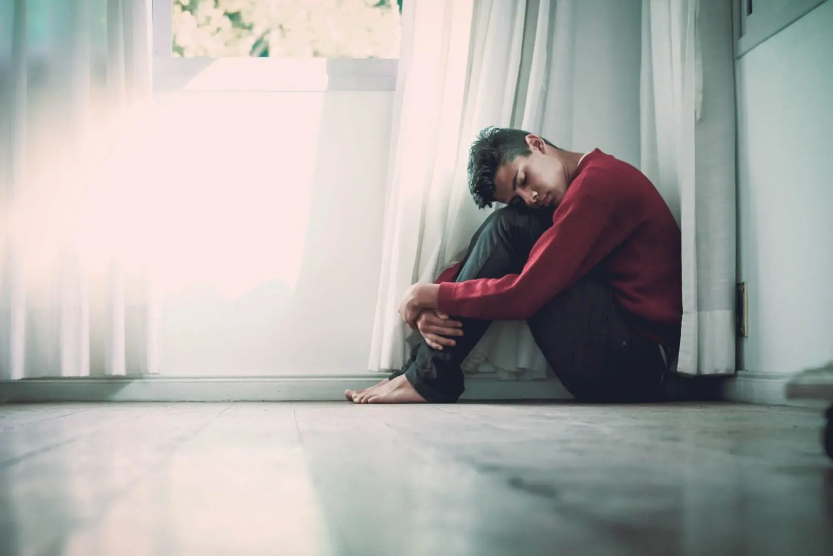 Young depressed man sitting on floor