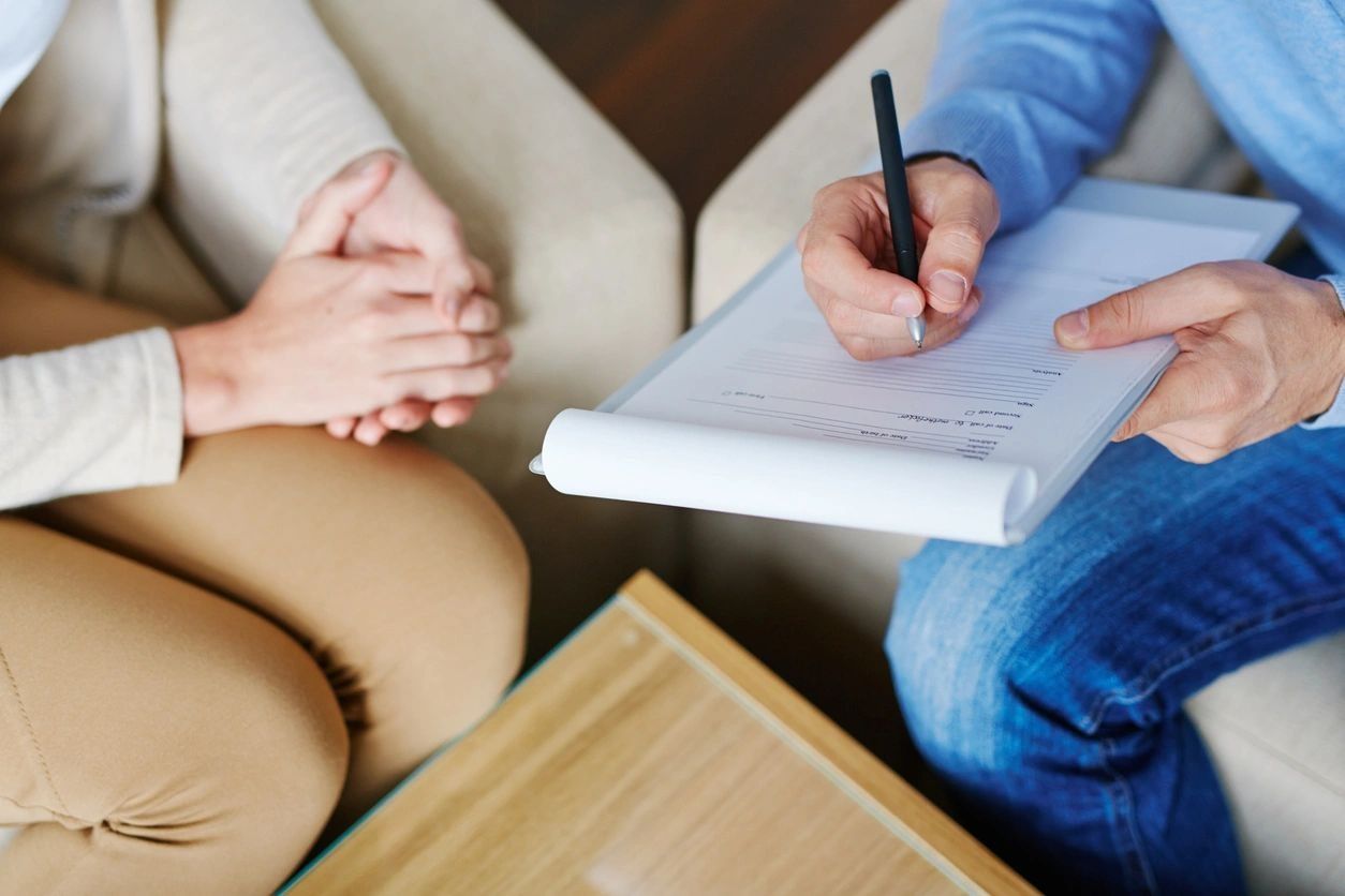 Hands of psychiatrist filling in medical document with patient
