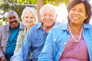 Smiling group of four older adults outdoors.
